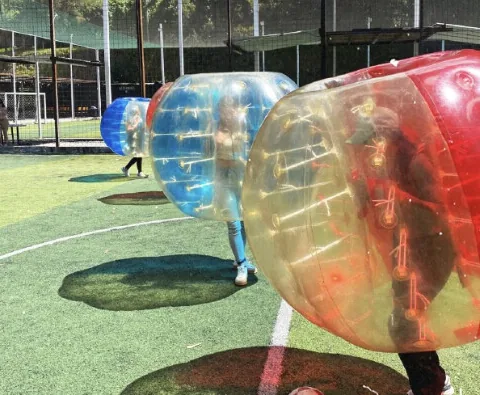 Esferas de bubble ball roja, azul y transparente en juego sobre una cancha sintética de fútbol