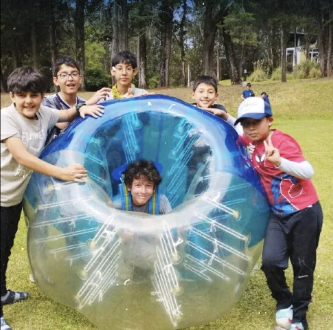 Niños jugando dentro de las esferas de bubble ball sobre el césped